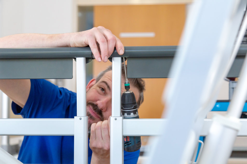 Ein Mitarbeiter vom Serviceteam Simon nutzt einen Akkuschrauber zur Wartung oder Montage eines medizinischen Geräts.
