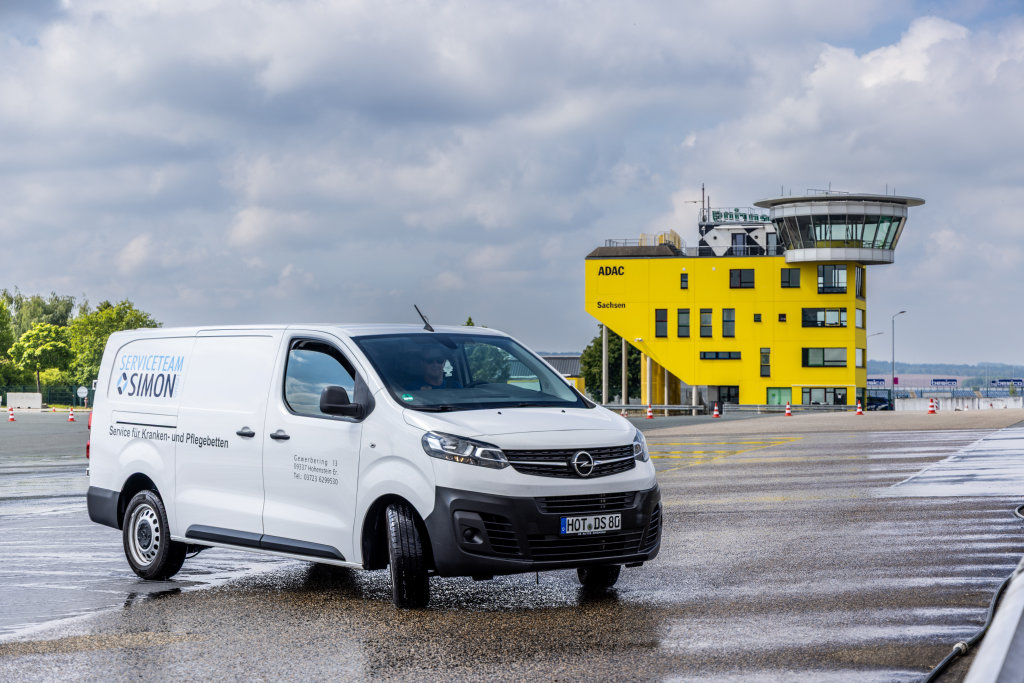 Lieferwagen des Serviceteams Simon vor einem ADAC-Gebäude in Sachsen bei bewölktem Wetter.